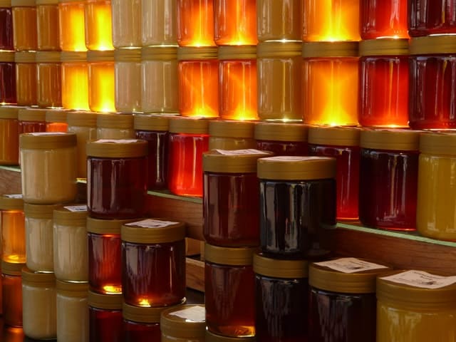 Several jars of honey of different color, hummingbee