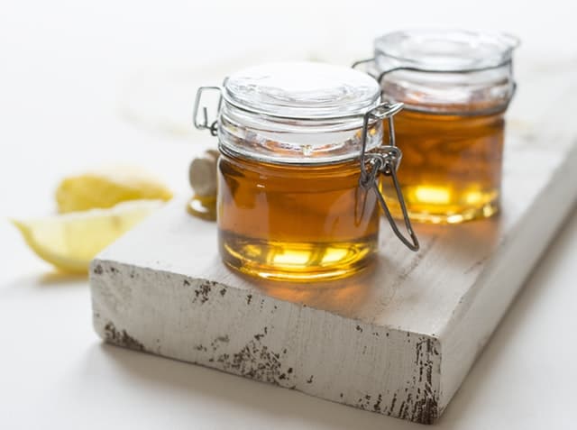 Two jars of honey on a board, humming bee